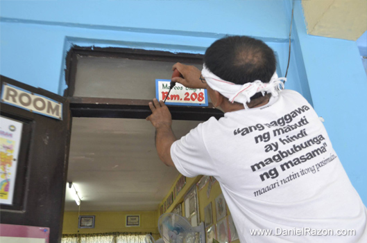 A UNTV volunteer fastens a room number sign in Tunasan Elementary School in Muntinlupa City last May 18, 2015. (Photo courtesy of Photoville International)