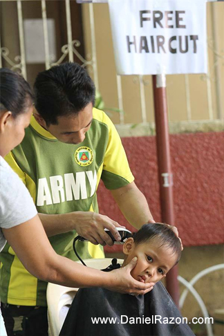 A mom helps her son gets his free haircut from an Army staff at the People’s Day outreach program of UNTV in Malibay, Pasay City. (Rey Calinawan Vercide | Photoville International)
